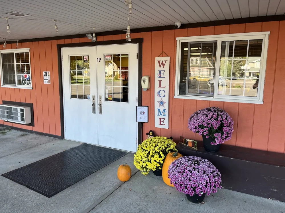 The front door of Lola's at 19 S Main St, with a Welcome sign, pumpkins and potted flowers